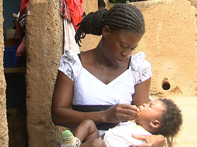 Photo: Mother administering SMC to child in West Africa