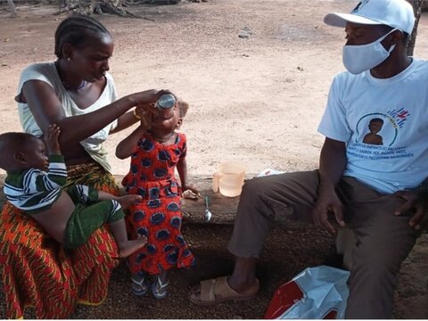 Photo: Mother administering SMC to child in Guinea